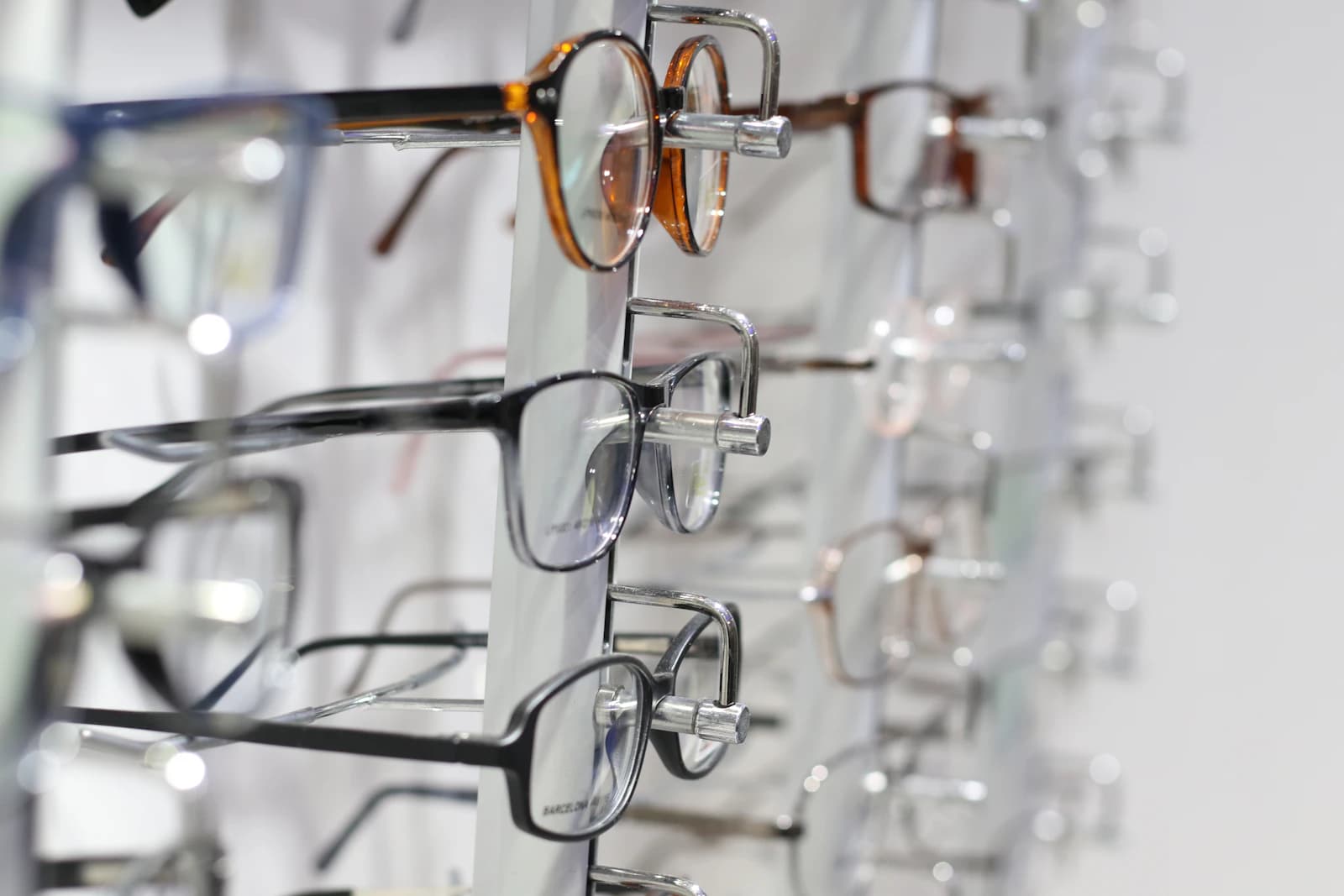 Acetate and metal optical frames in several sizes and colors lined up on a display rack, ready for a wide-face fitting