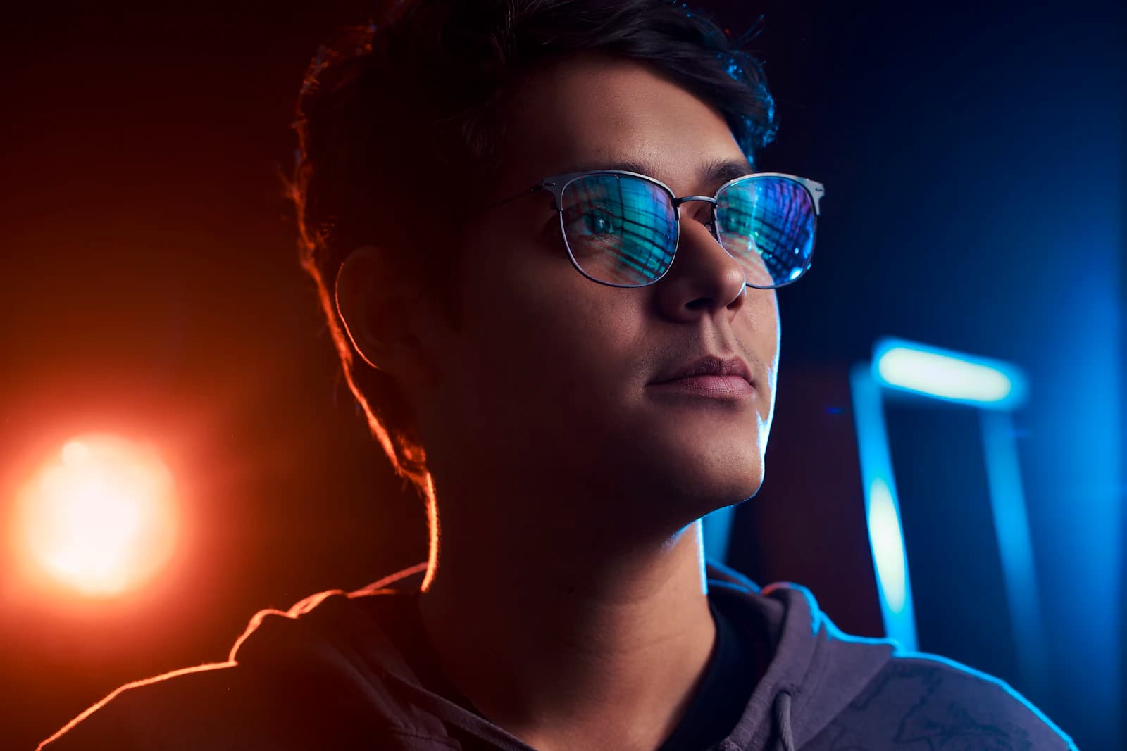 Two eyeglass lenses compared under light, each showing a different blue-light coating reflection
